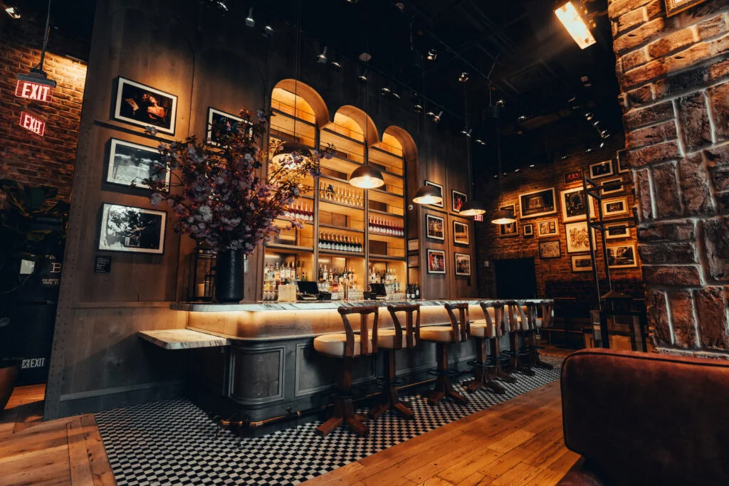 Warmly lit bar interior with custom wood shelving and seating