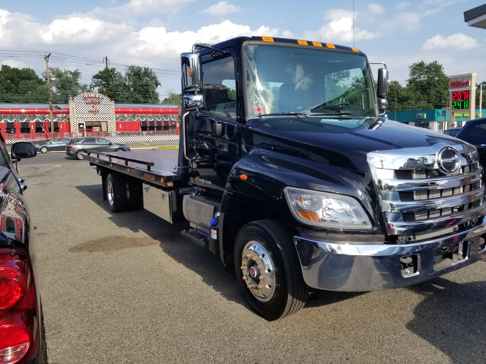 Black flatbed tow truck parked beside a road